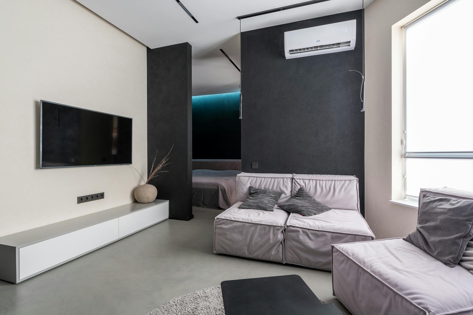 Modern living room with wall-mounted air conditioning unit on a dark feature wall